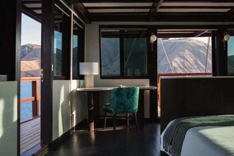 a room with a bed and a desk aboard VELA Yacht for Charter