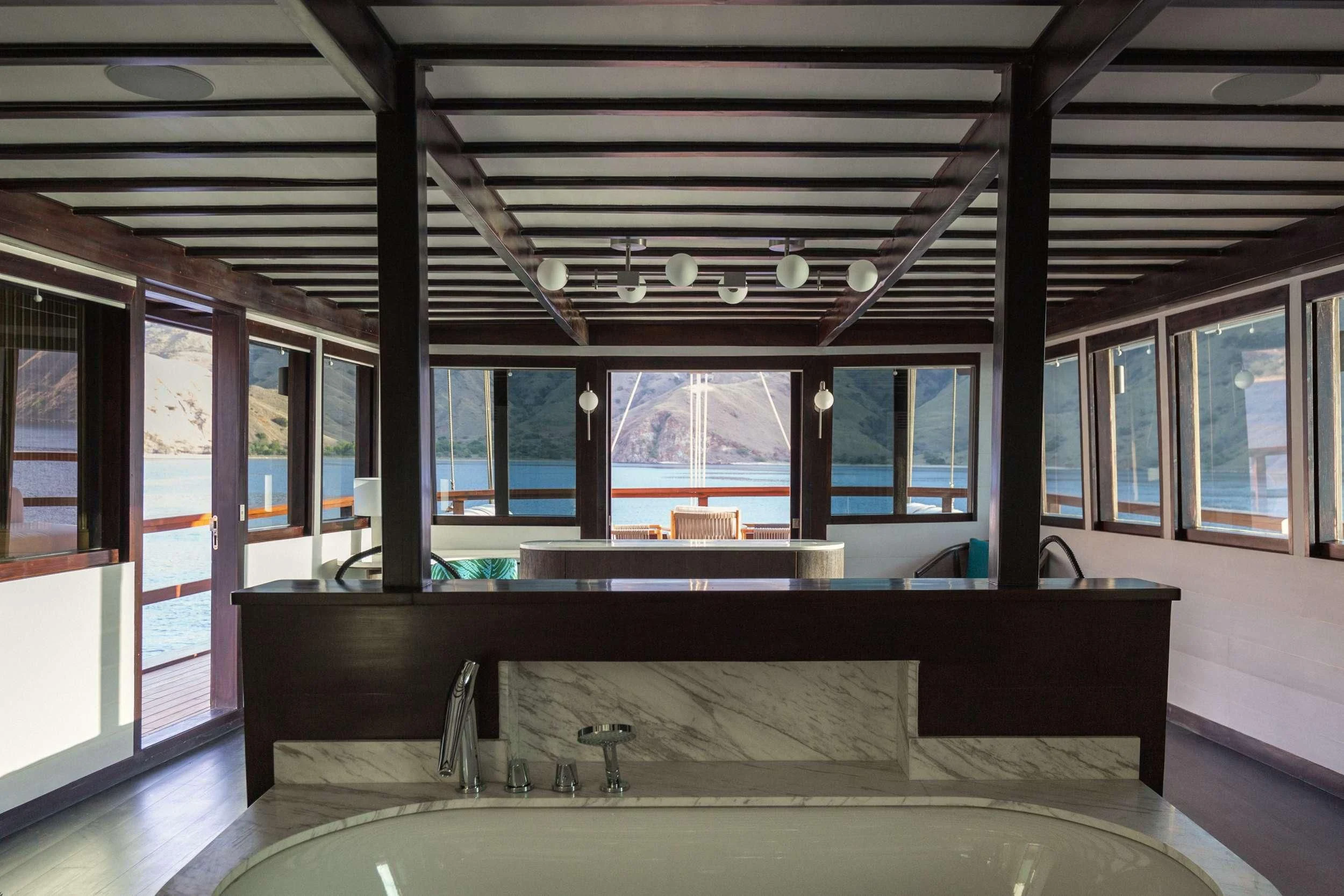 a room with a pool table and a large window aboard VELA Yacht for Charter
