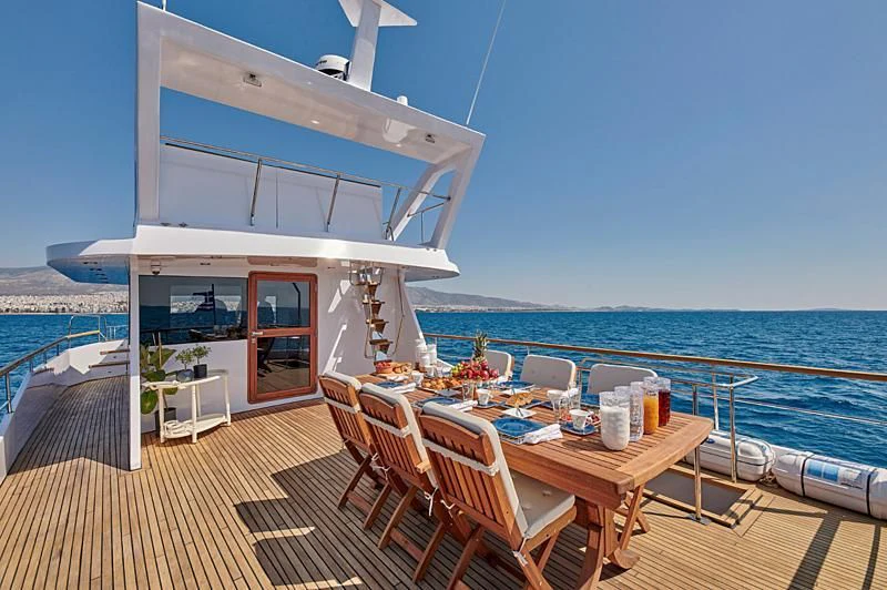 a deck with a table and chairs on it aboard WIDE LIBERTY Yacht for Sale