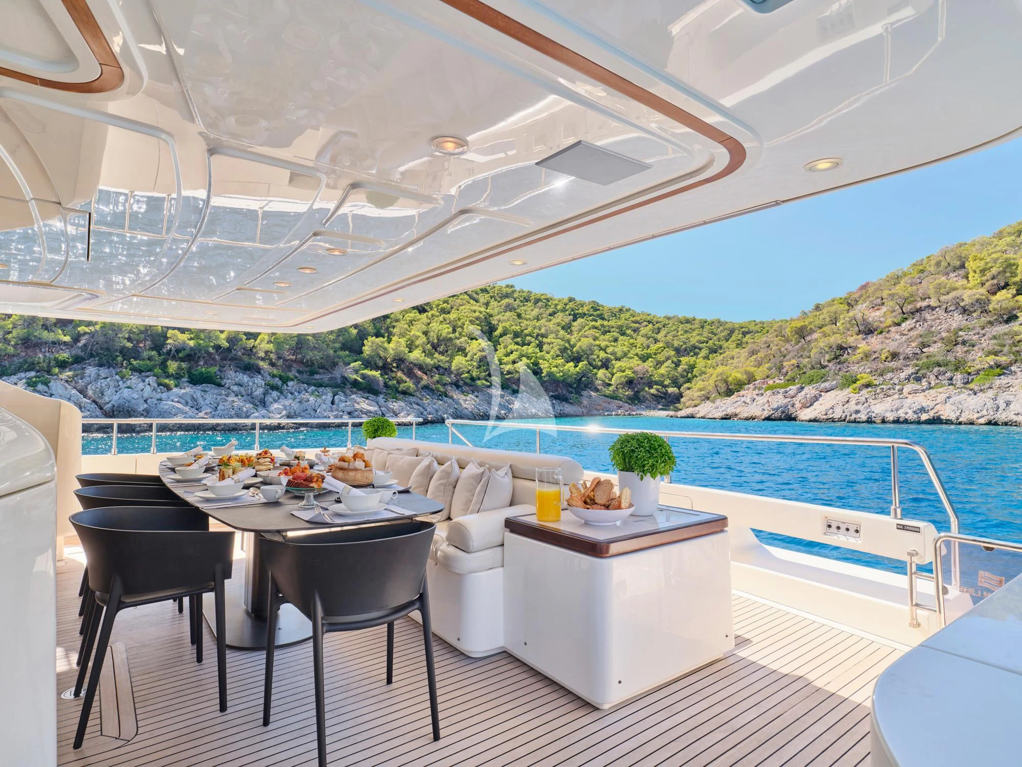 a table and chairs on a balcony overlooking a body of water aboard SEVEN S Yacht for Charter