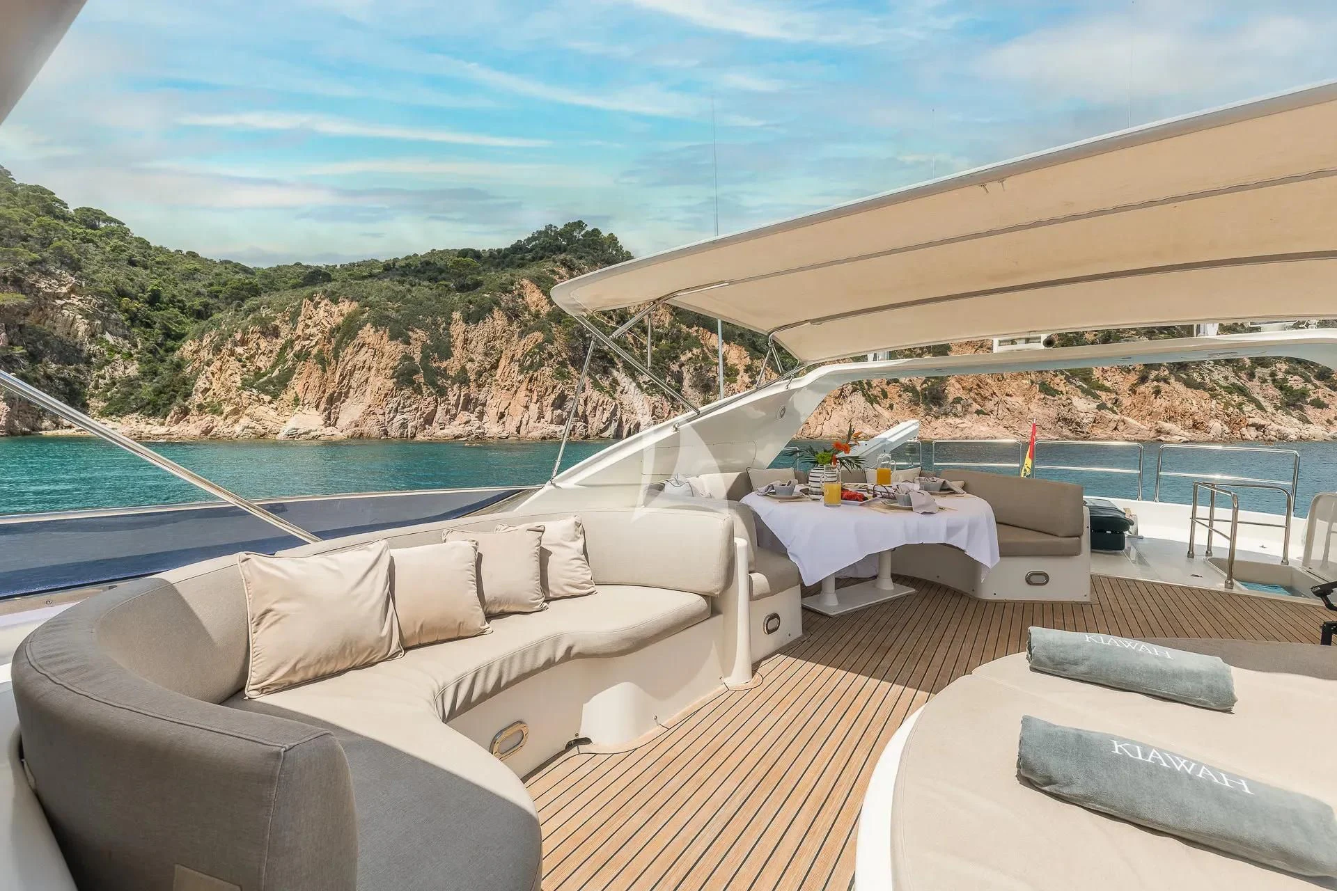 a deck with a pool and a beach and mountains in the background aboard KIAWAH II Yacht for Sale