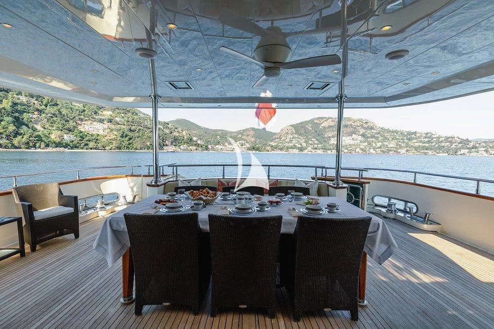 a table set for a meal on a deck overlooking a large body of water aboard W EXPLORER Yacht for Sale