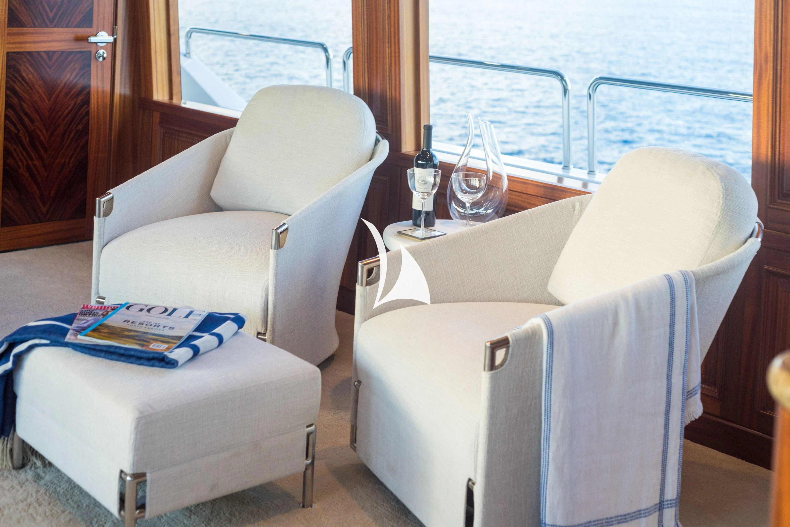 a couple of white chairs next to a table with a book on it aboard TRUST FUN Yacht for Sale