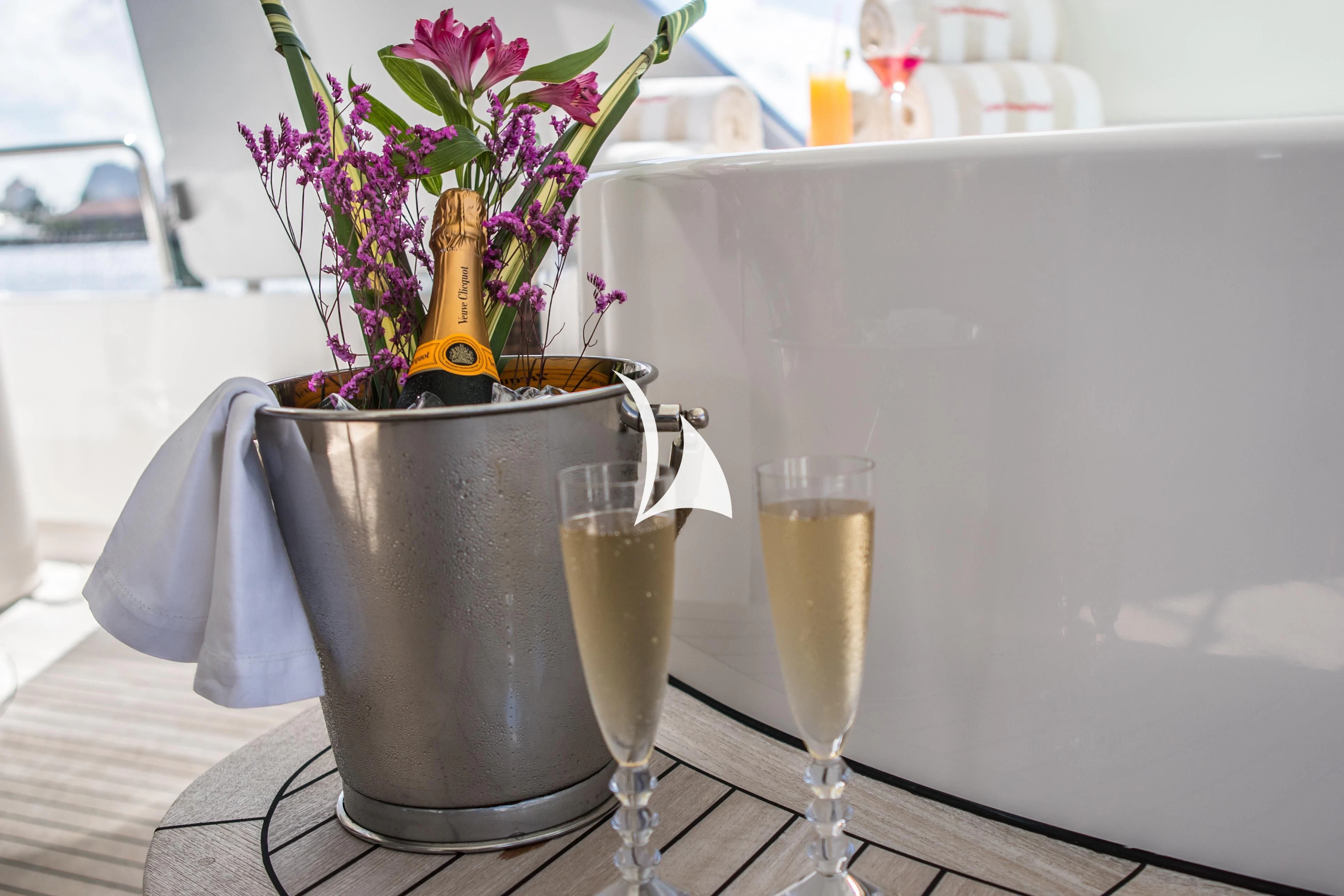 a vase of flowers sits on a table next to a glass of champagne aboard TRUST FUN Yacht for Sale
