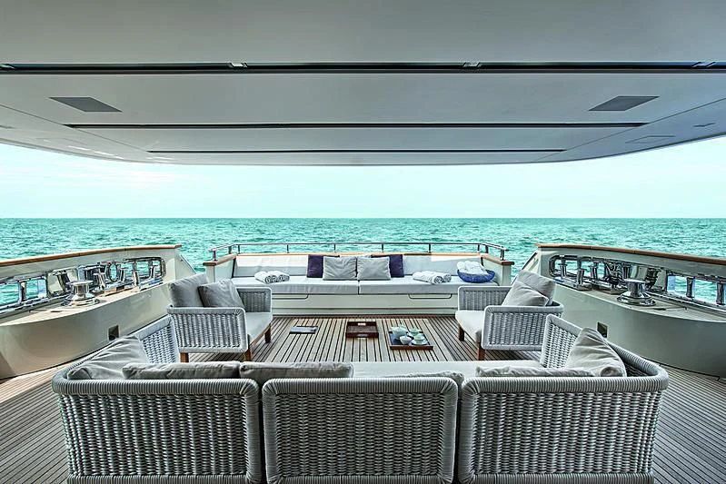 a deck with chairs and a table on it aboard Y4H Yacht for Sale