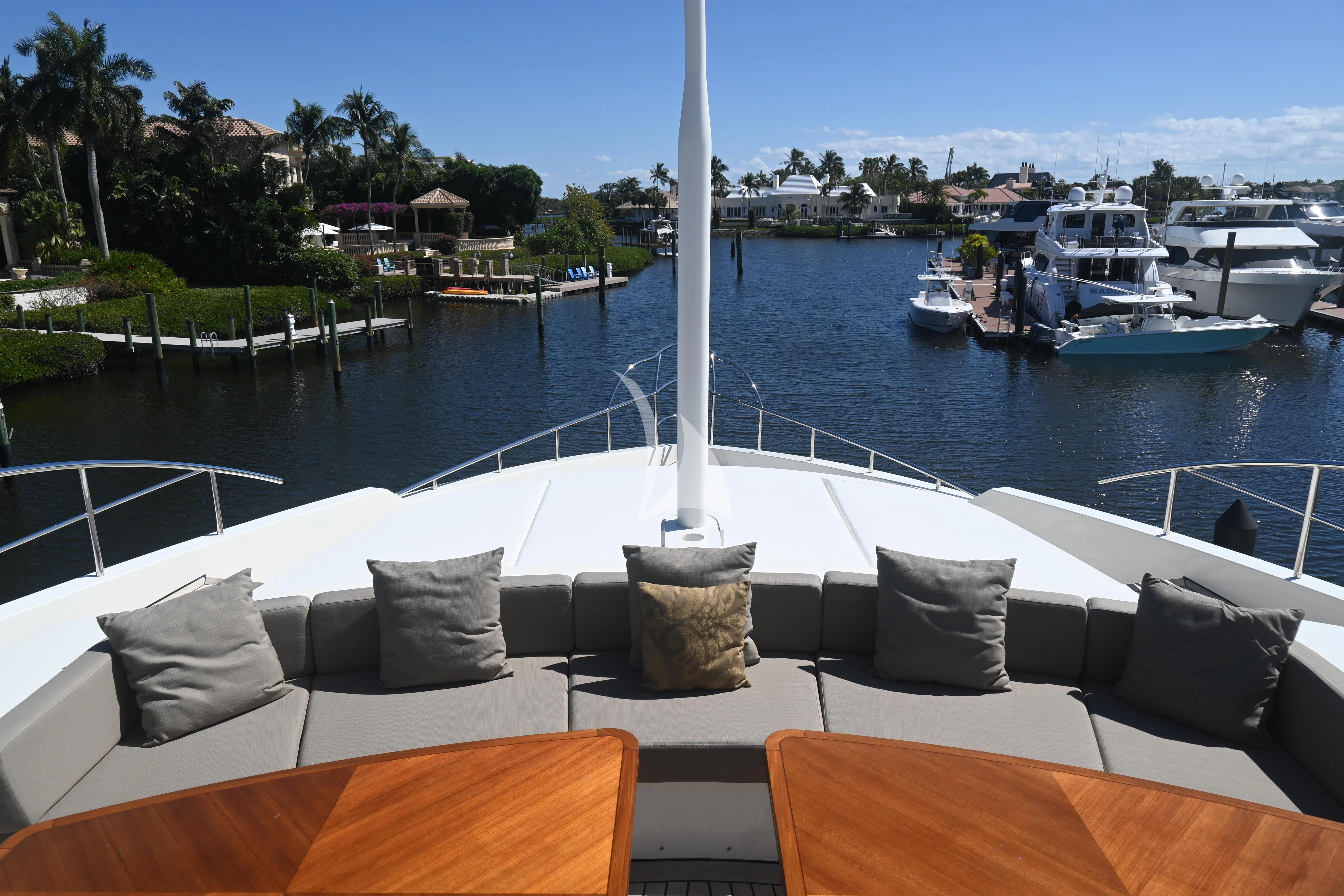 a deck with chairs and a table with boats in the water aboard KIMBERLIE Yacht for Sale