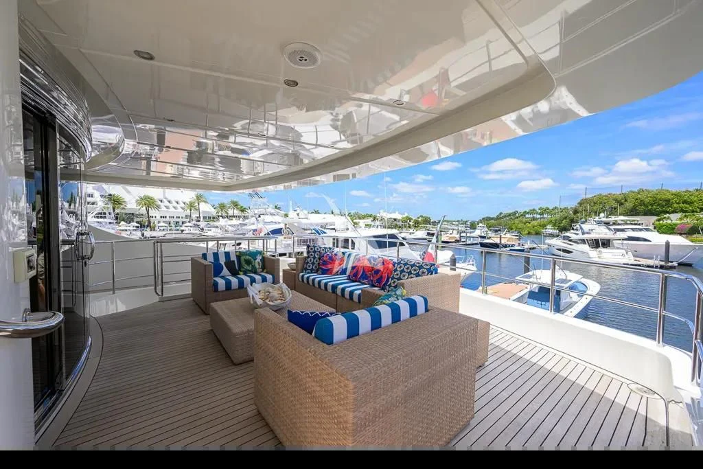 a lounge area with a pool and a deck with boats and a large building with trees and blue aboard KIMBERLIE Yacht for Sale