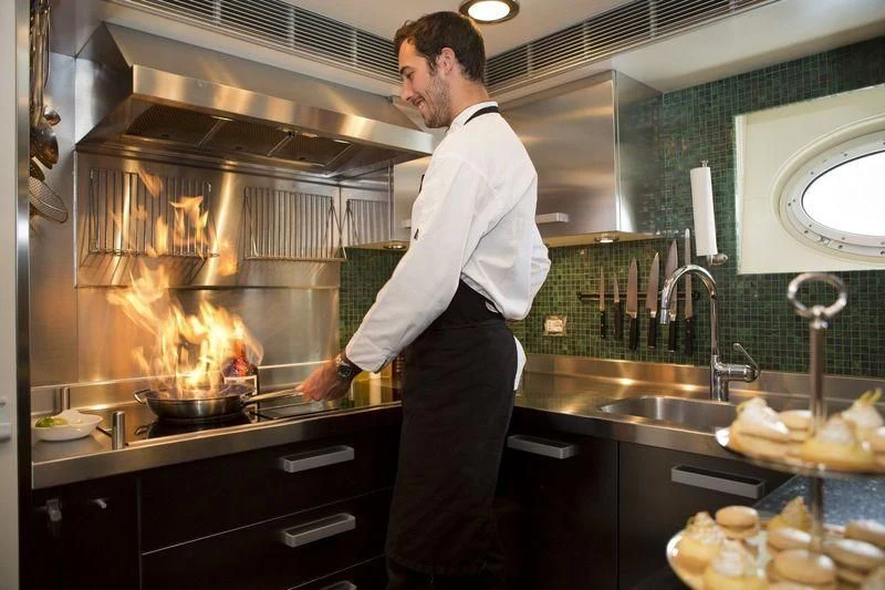 a man cooking in a kitchen aboard STEALTH Yacht for Sale