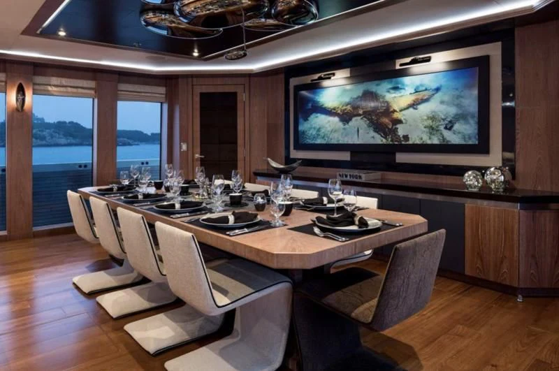 a large dining table with a large screen on the wall aboard STEALTH Yacht for Sale