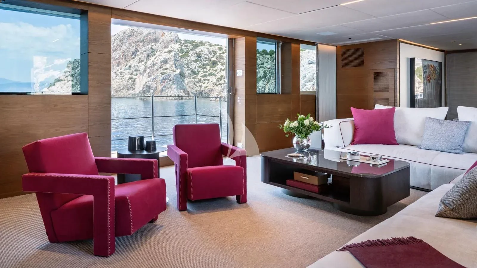 a living room with red chairs and a table with a large window aboard NAIA Yacht for Sale