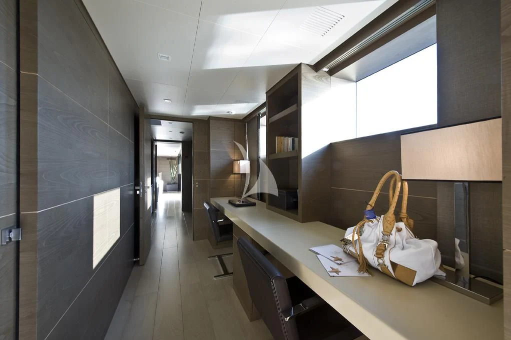 a room with a desk and a chair and a lamp aboard NAIA Yacht for Sale