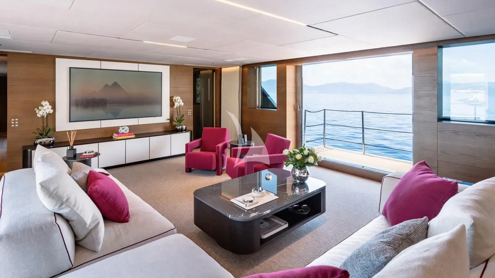 a living room with a large flat screen television and pink pillows aboard NAIA Yacht for Sale