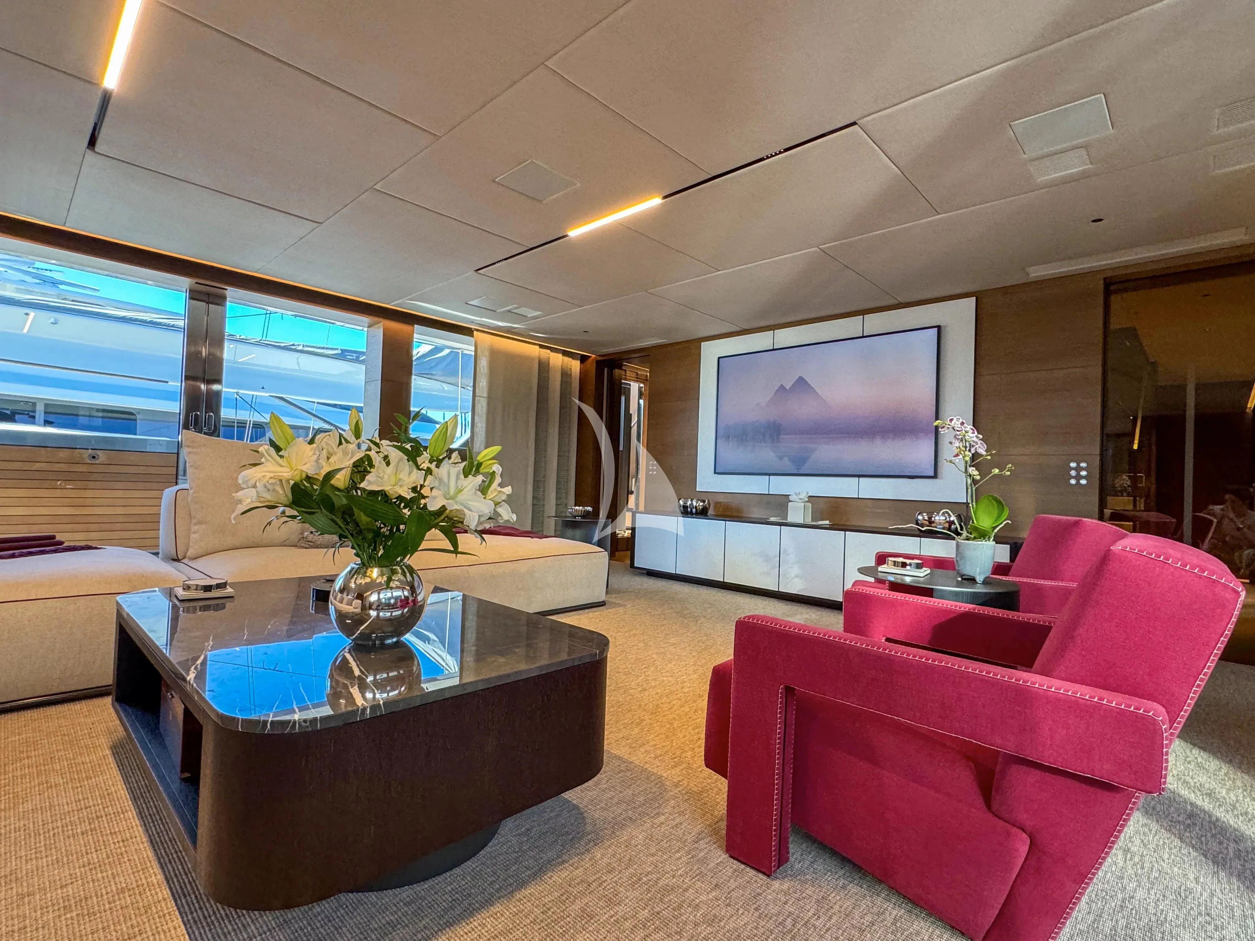 a living room with a tv and pink chairs aboard NAIA Yacht for Sale