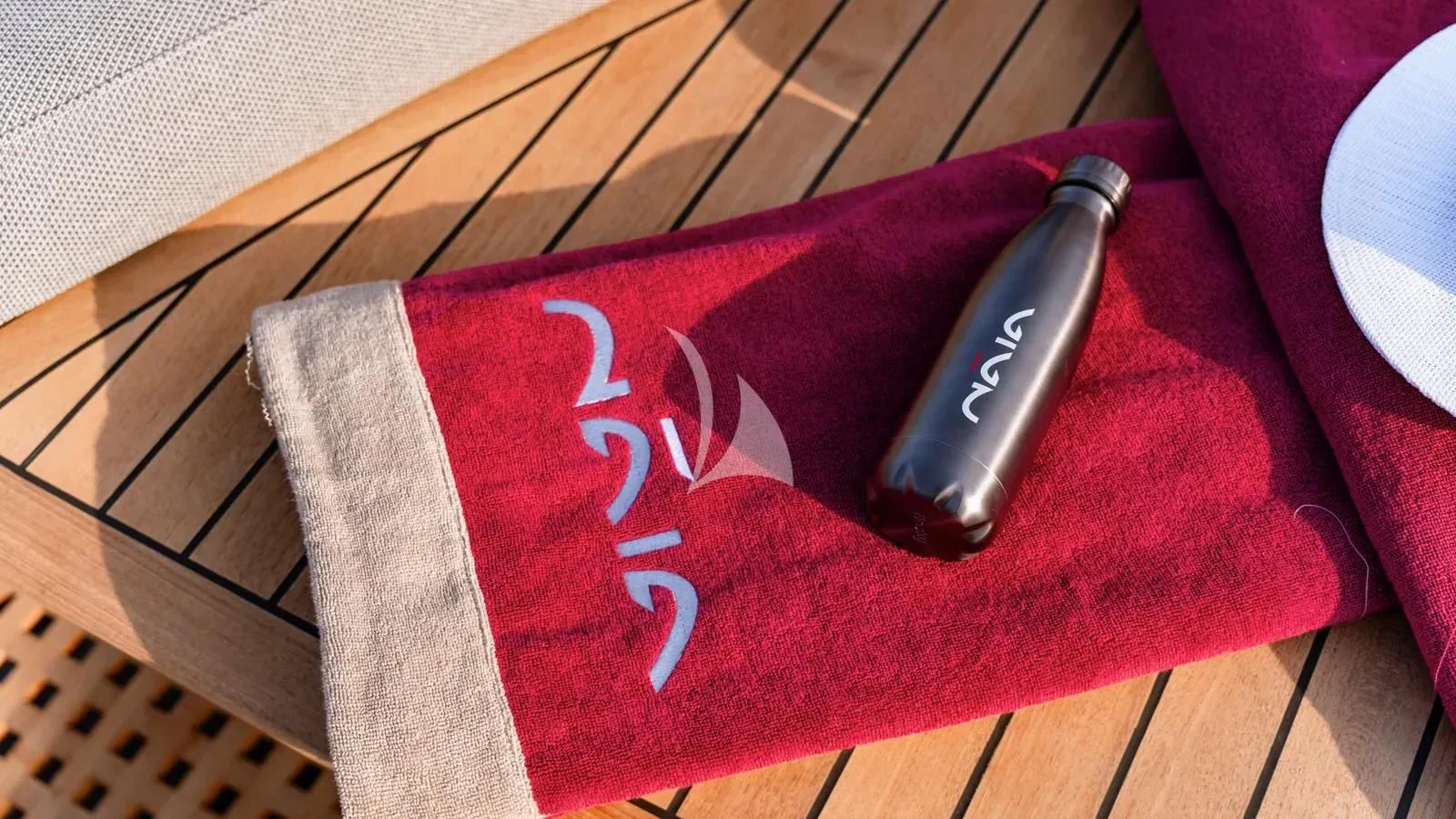 a bottle of soda on a red blanket aboard NAIA Yacht for Sale