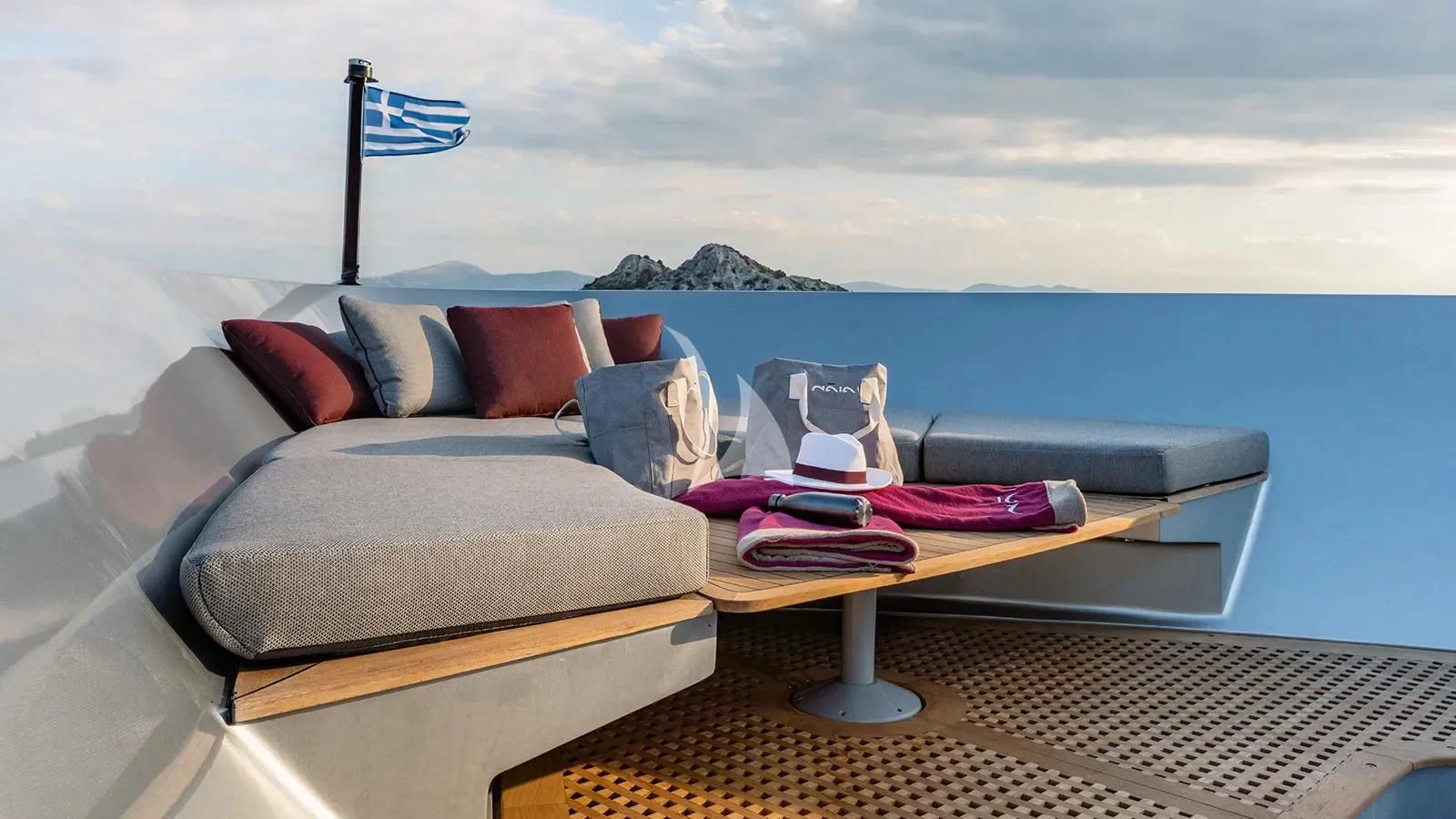 a couch with pillows and a flag on it aboard NAIA Yacht for Sale