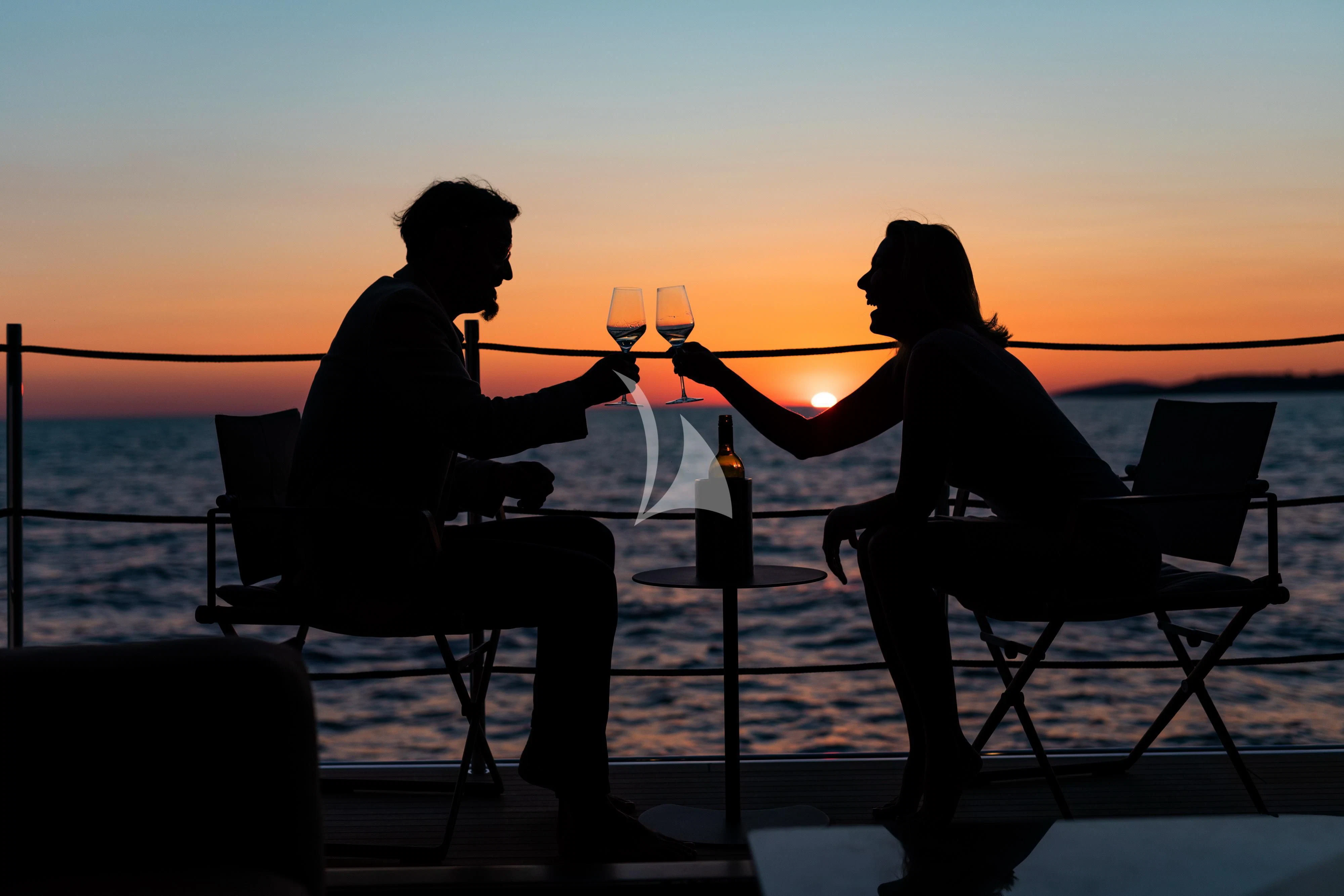 a man and woman sitting on a bench and holding wine glasses aboard NOOR II Yacht for Charter