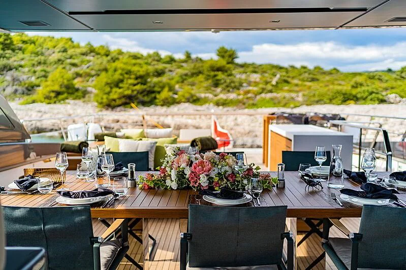 a table with chairs and a view of a city aboard NOOR II Yacht for Charter