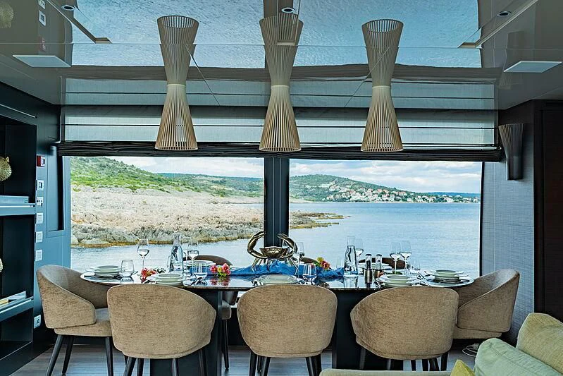 a table with chairs and a large window with a view of the water aboard NOOR II Yacht for Charter