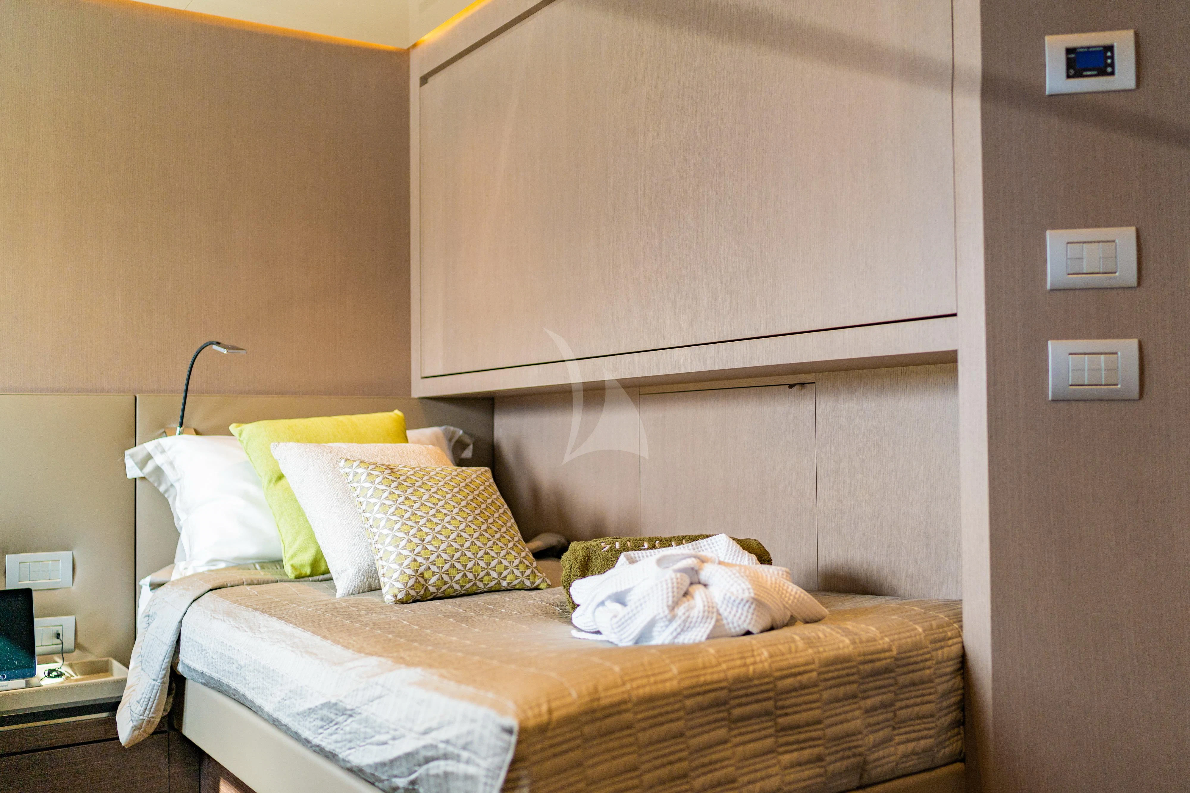 a bed with yellow pillows aboard NOOR II Yacht for Charter