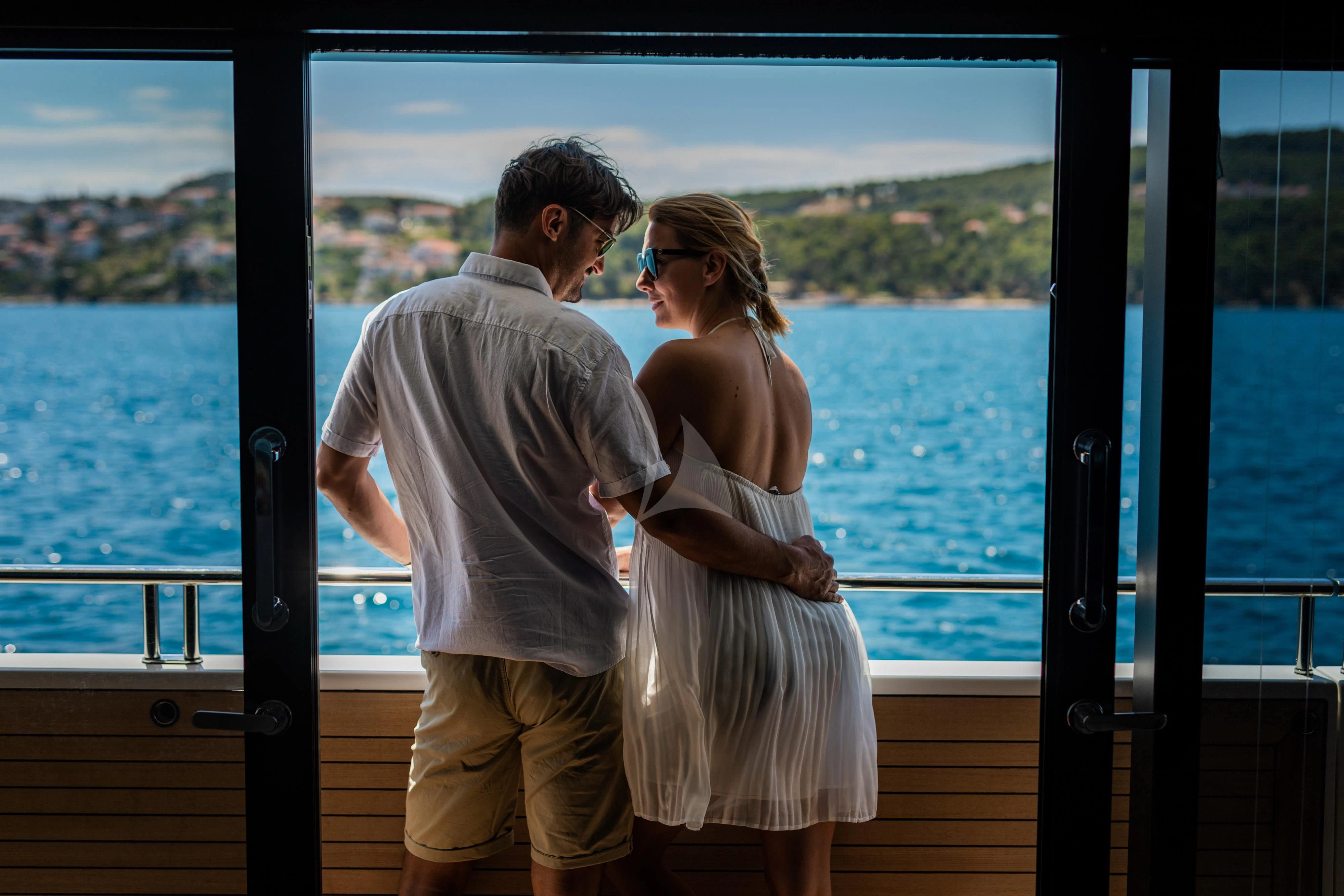a man and woman kissing on a balcony aboard NOOR II Yacht for Charter