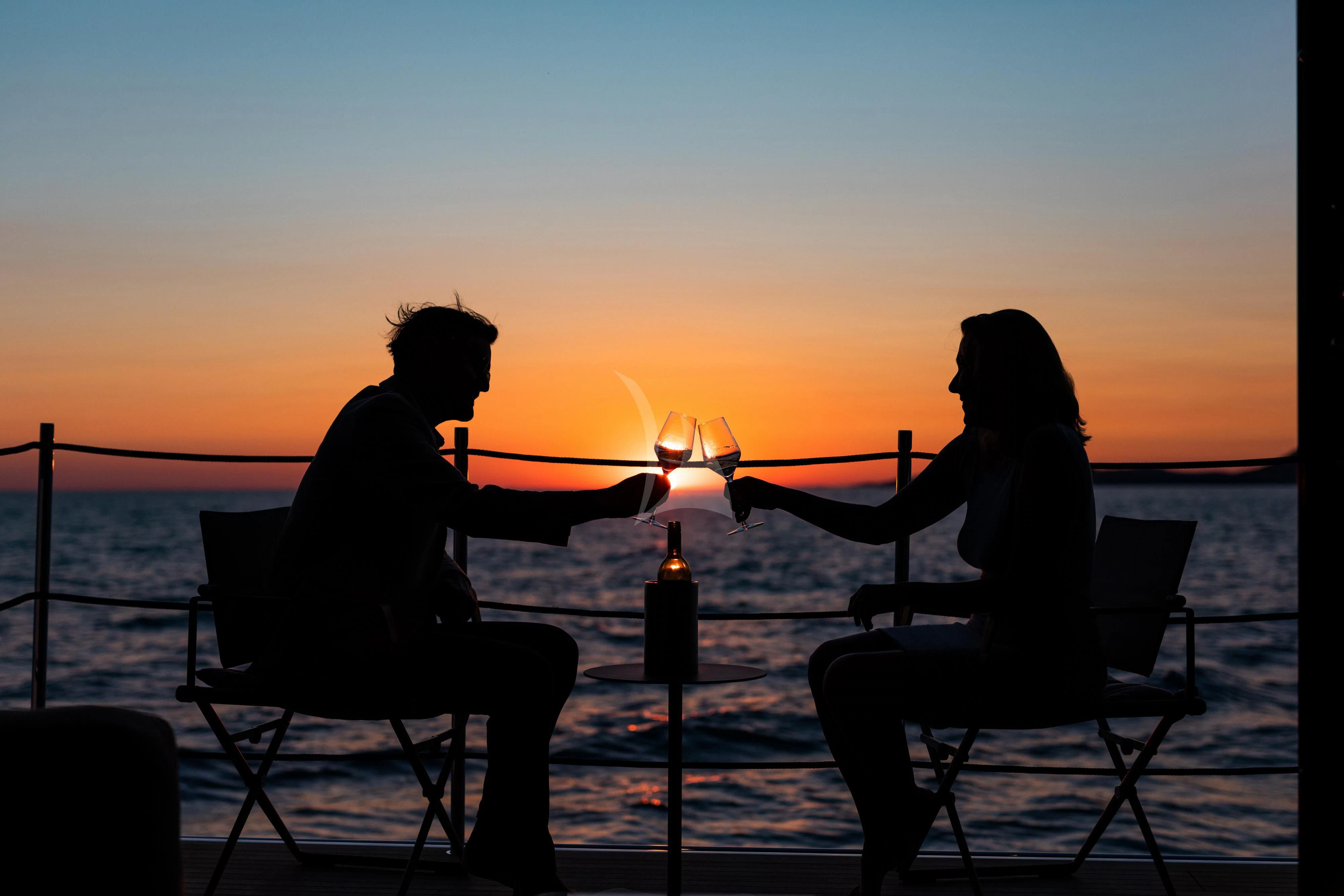 a couple sitting in chairs in front of a fire aboard NOOR II Yacht for Charter