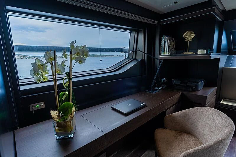 a desk with a vase of flowers and a tablet on it aboard NOOR II Yacht for Charter