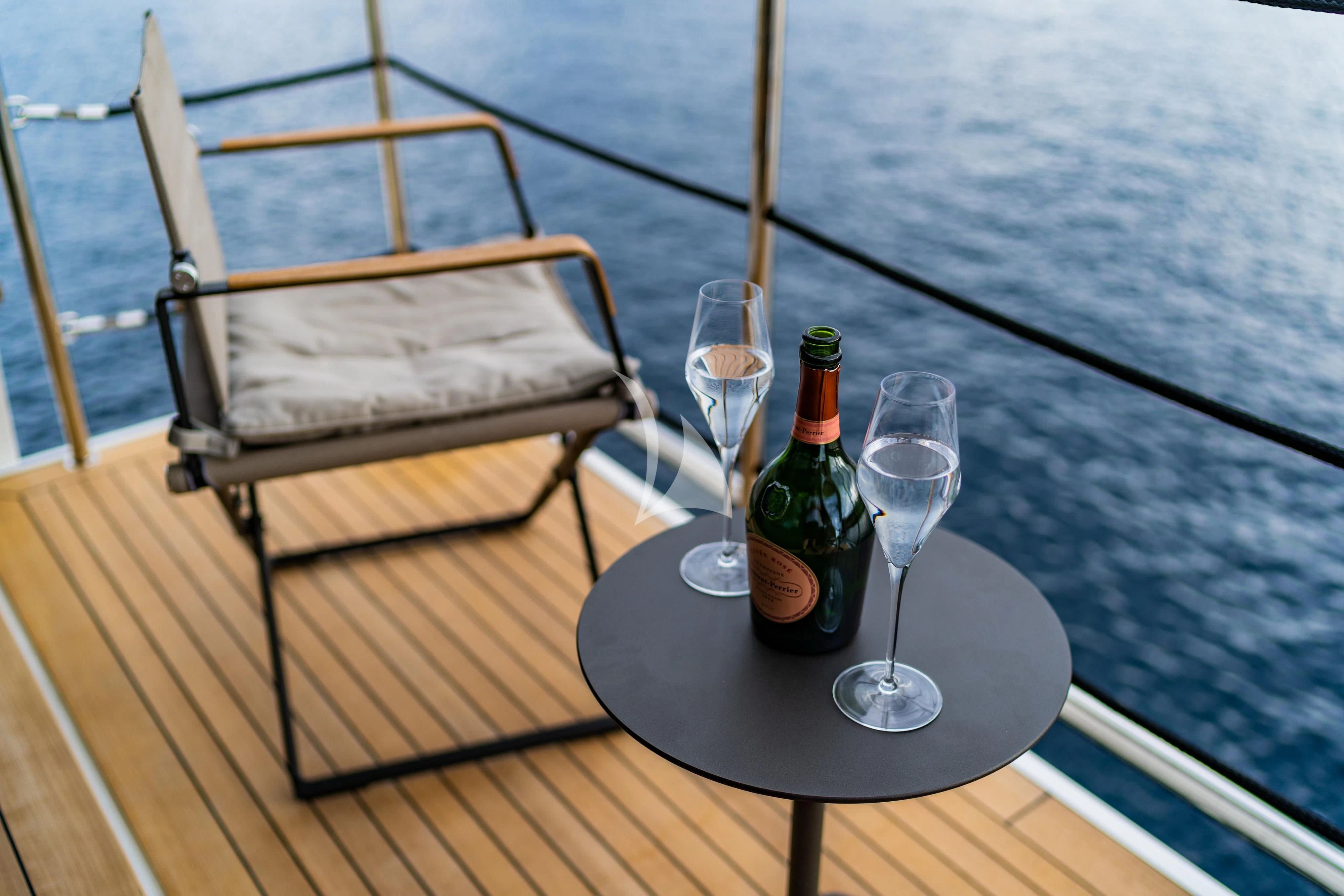 a bottle of wine and two glasses on a table aboard NOOR II Yacht for Charter