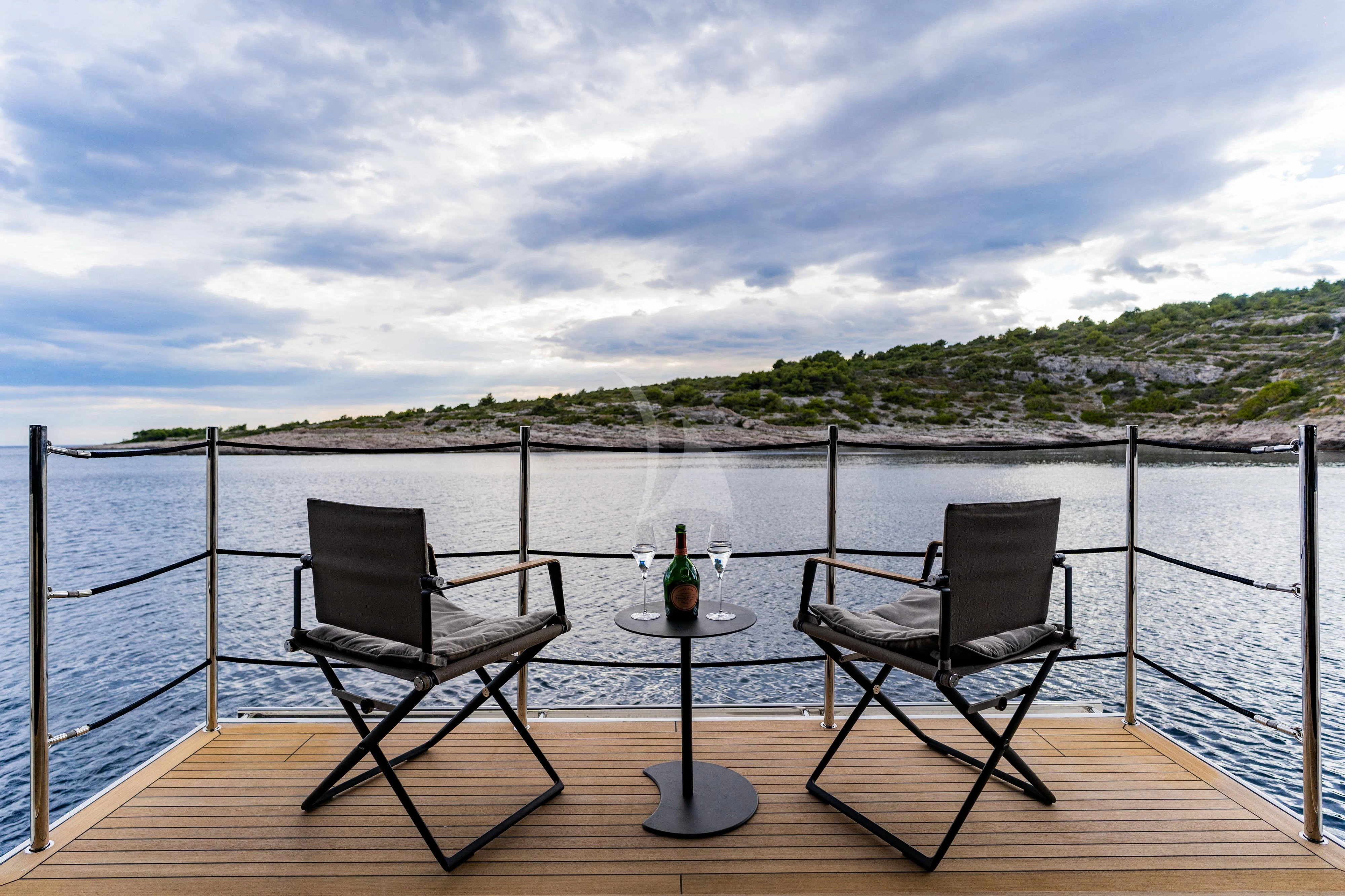 a couple chairs on a deck overlooking a body of water aboard NOOR II Yacht for Charter