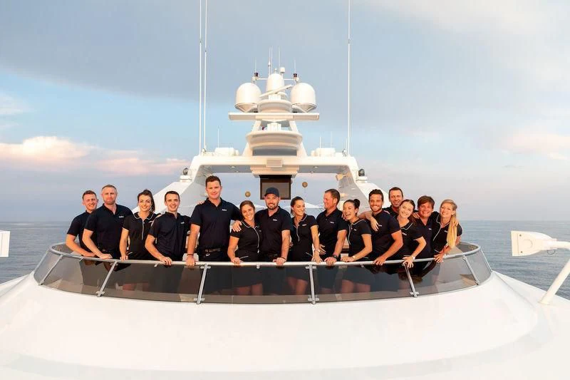 a group of people posing for a photo in front of a large ship aboard TREEHOUSE Yacht for Sale