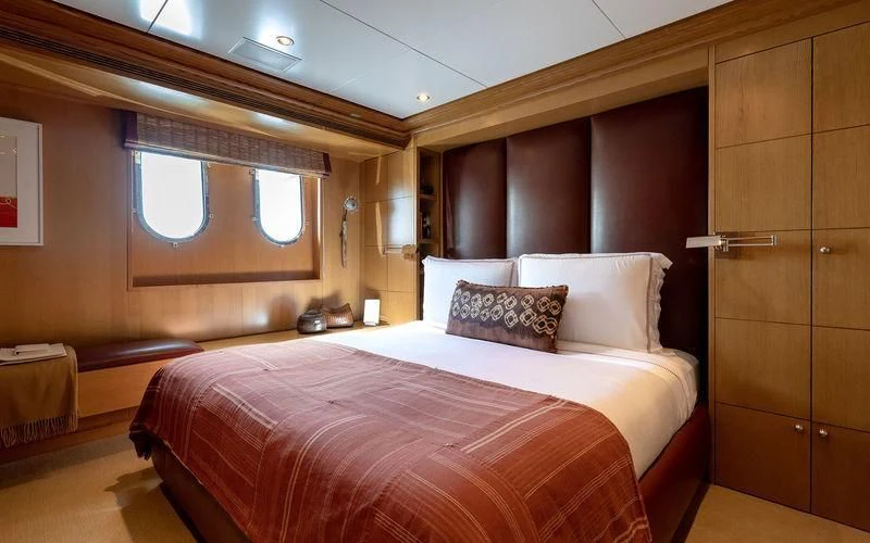 a room with a bed and a wooden cabinet aboard TREEHOUSE Yacht for Sale