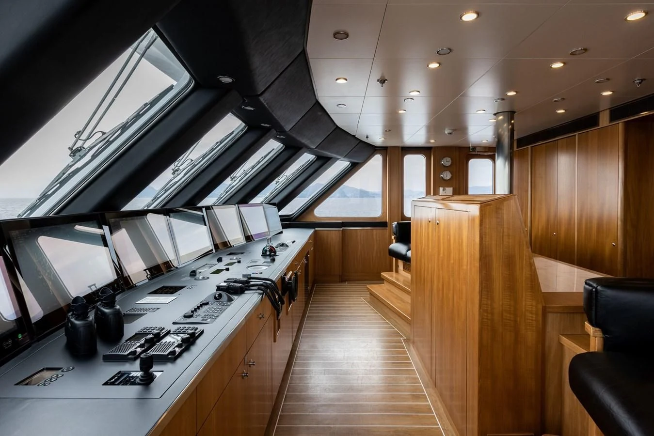 a long wood hallway with a large white counter and black chairs aboard TREEHOUSE Yacht for Sale