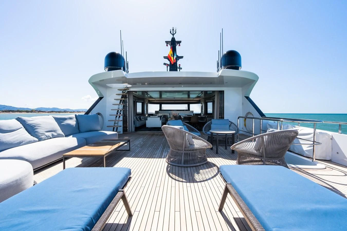 a deck with a table chairs and a person on a ladder on a boat aboard ZOUT Yacht for Sale