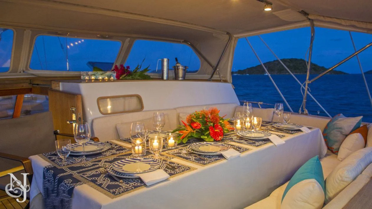 a table with wine glasses and a couch in a tent aboard WISDOM Yacht for Sale