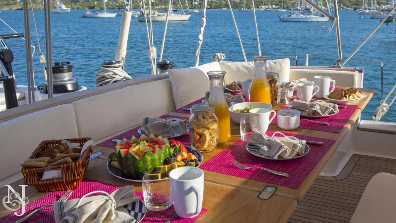 a table with food and drinks on it by a body of water aboard WISDOM Yacht for Sale