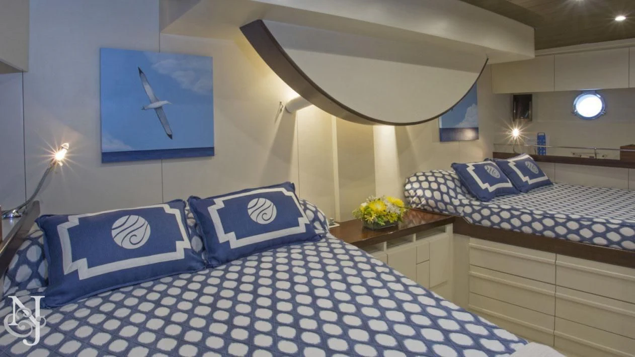 a room with a bed and a table with blue and white pillows aboard WISDOM Yacht for Sale