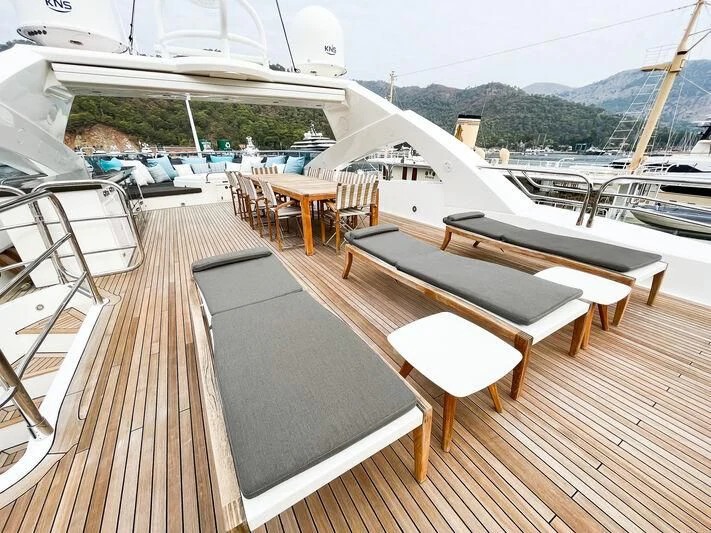 a deck with tables and chairs on it aboard IMAN Yacht for Sale