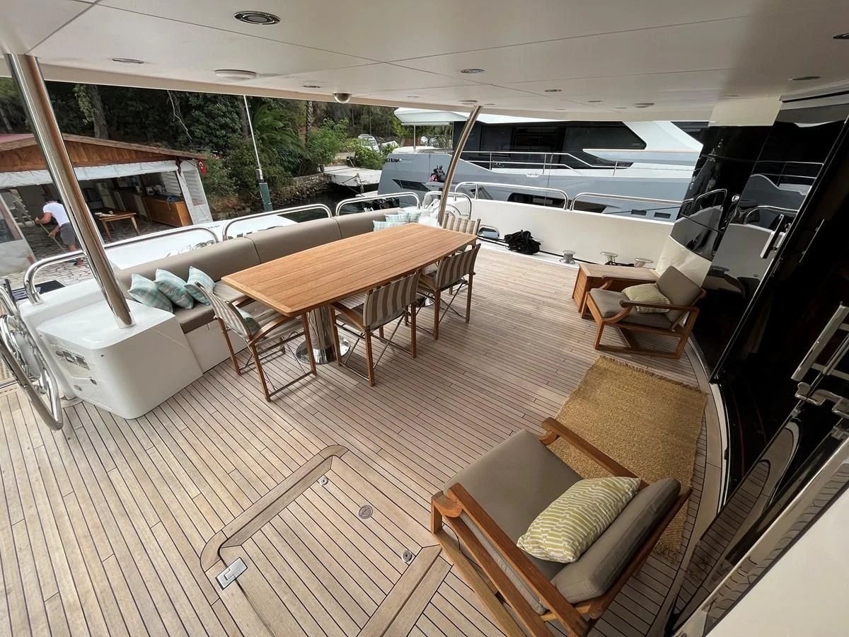 a room with a table chairs and a boat in the background aboard IMAN Yacht for Sale