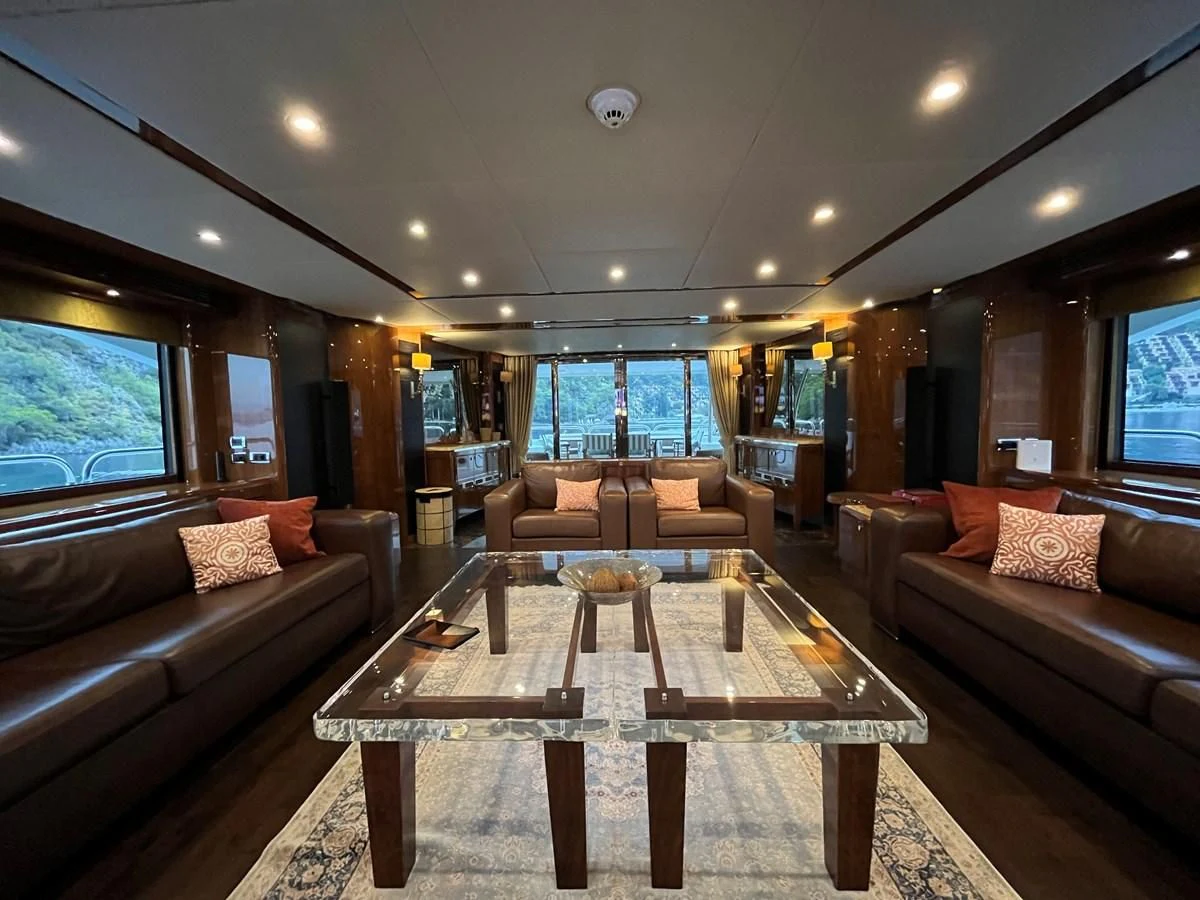 a living room with a table and couches aboard IMAN Yacht for Sale