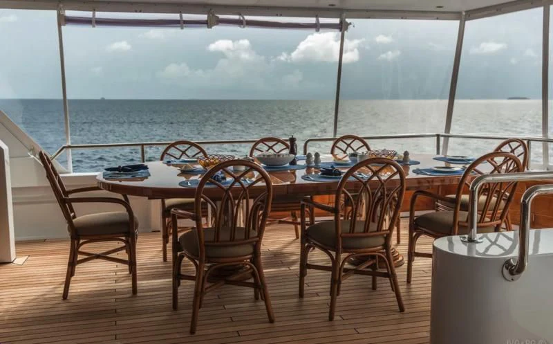 a table and chairs on a deck overlooking a body of water aboard BLUE STAR Yacht for Sale
