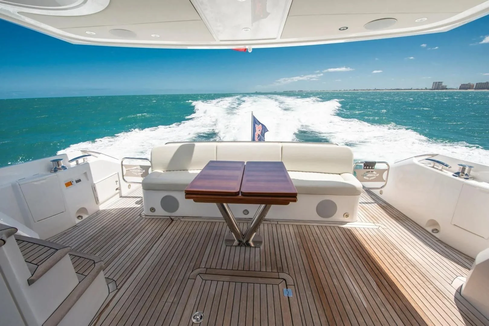 a deck with a table and chairs on it by a body of water aboard LIQUIDITY Yacht for Sale