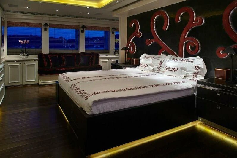a room with a bed and a window with red and white designs aboard ROCKET Yacht for Sale