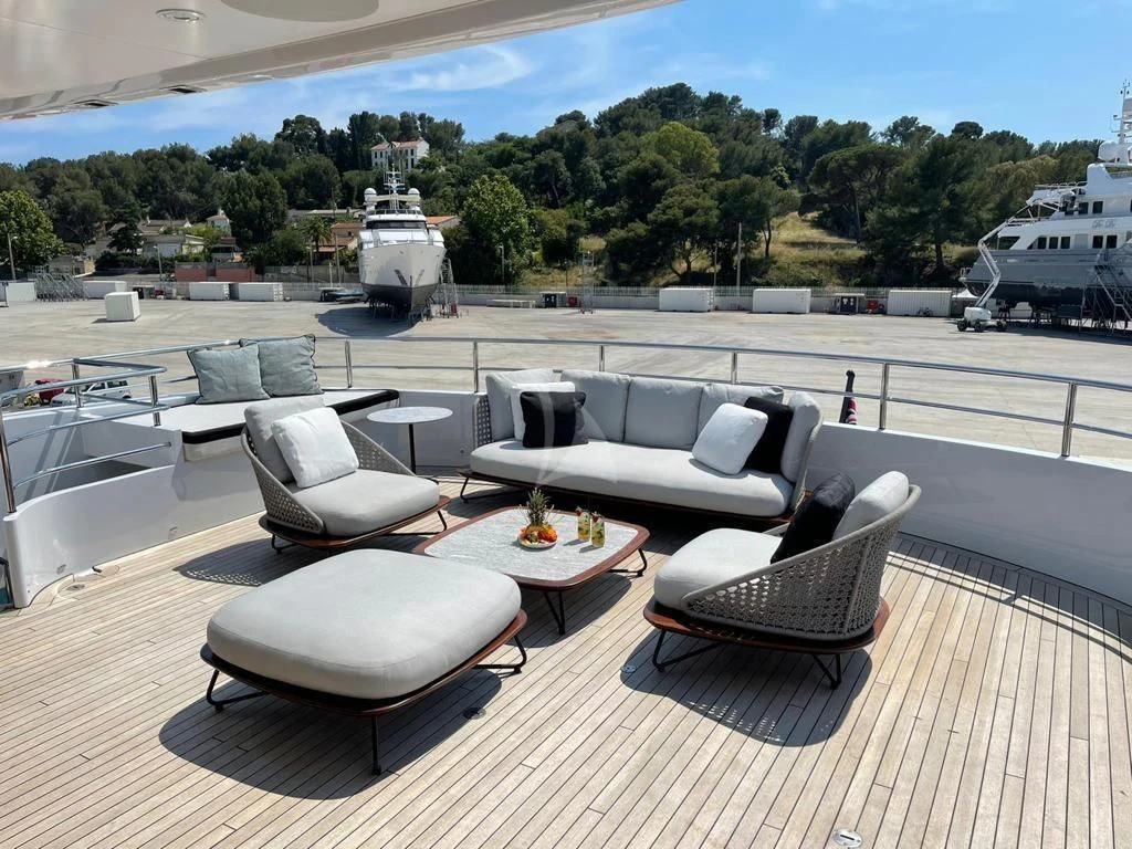 a room with a couch and a table and chairs on a deck aboard ROCKET Yacht for Sale