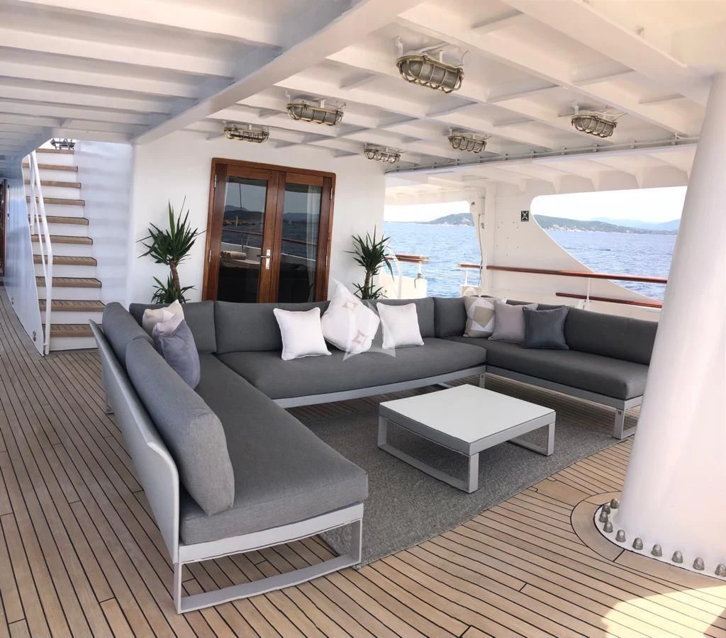 a living room with a large blue couch and a large pool aboard DIONEA Yacht for Sale