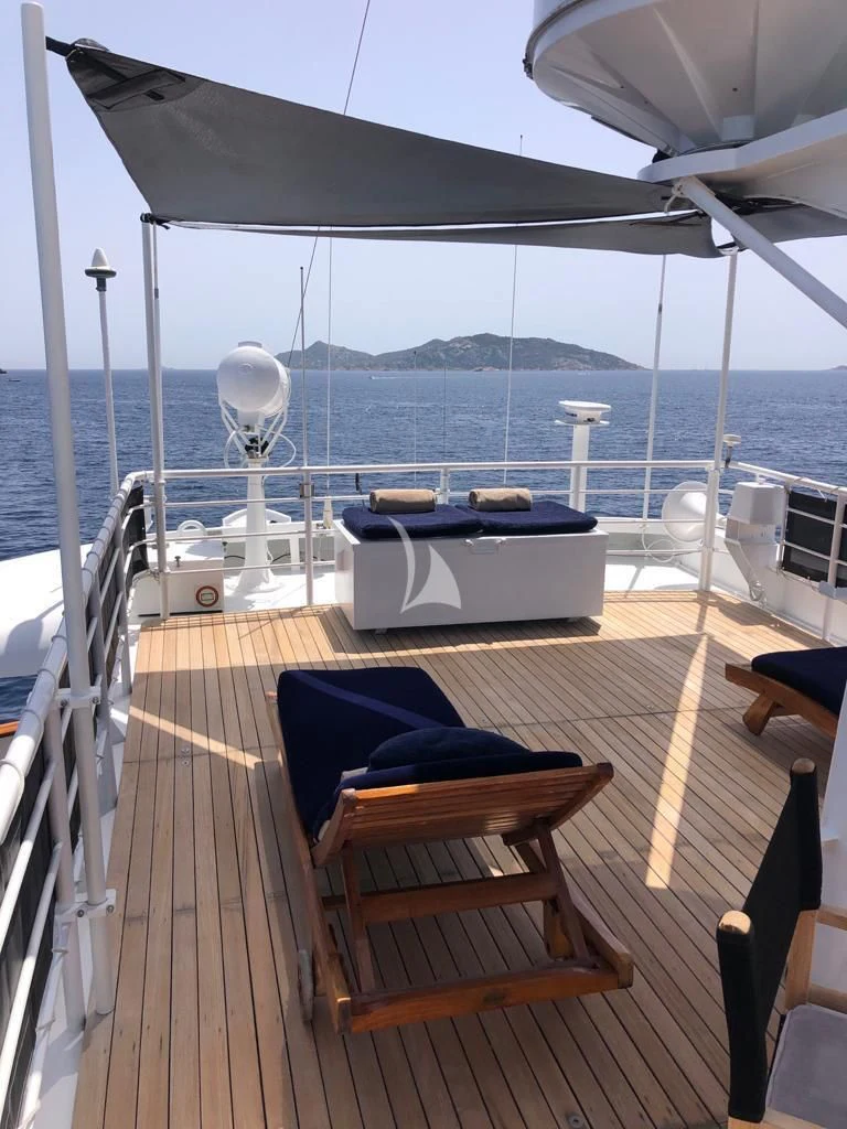 a deck with a table and chairs on it aboard DIONEA Yacht for Sale