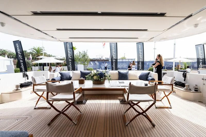 a room with a table chairs and people sitting in it aboard ELA & SEA Yacht for Sale