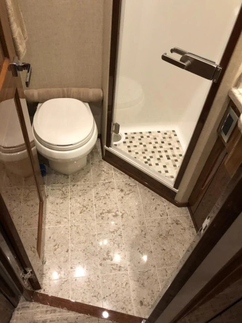 a bathroom with a toilet and a glass door aboard AFTER MIDNIGHT Yacht for Sale