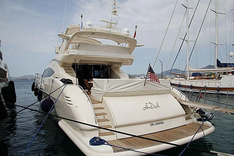 a white boat with a flag on it aboard ADA Yacht for Sale