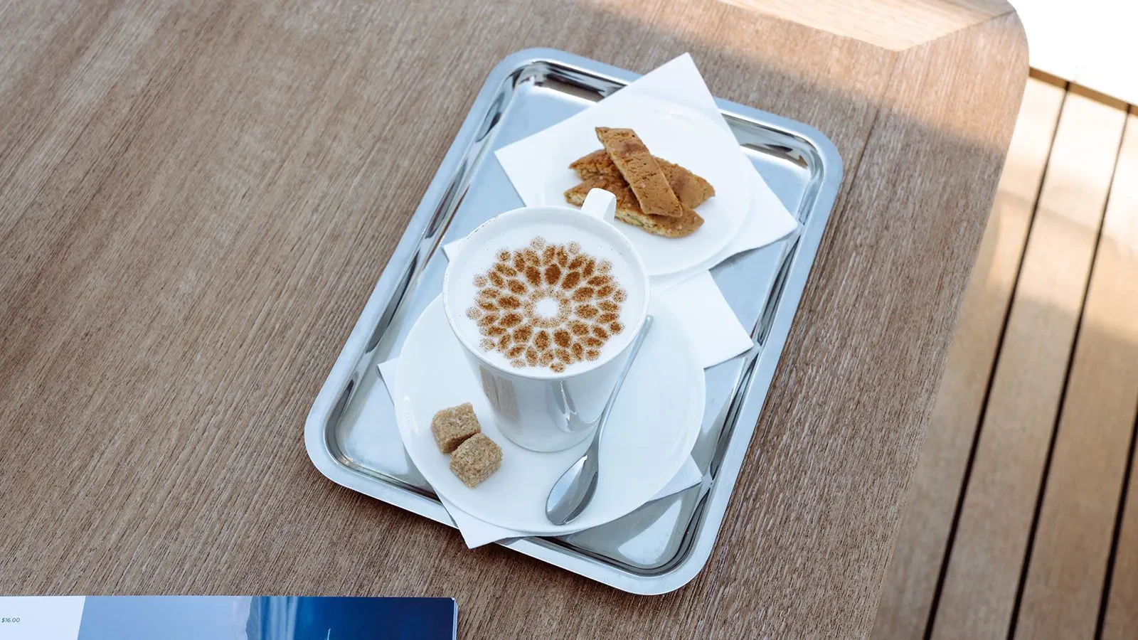 a cup of coffee and a croissant on a tray aboard AWAY Yacht for Charter