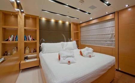 a room with a bed and a shelf with books on it aboard AWAY Yacht for Charter