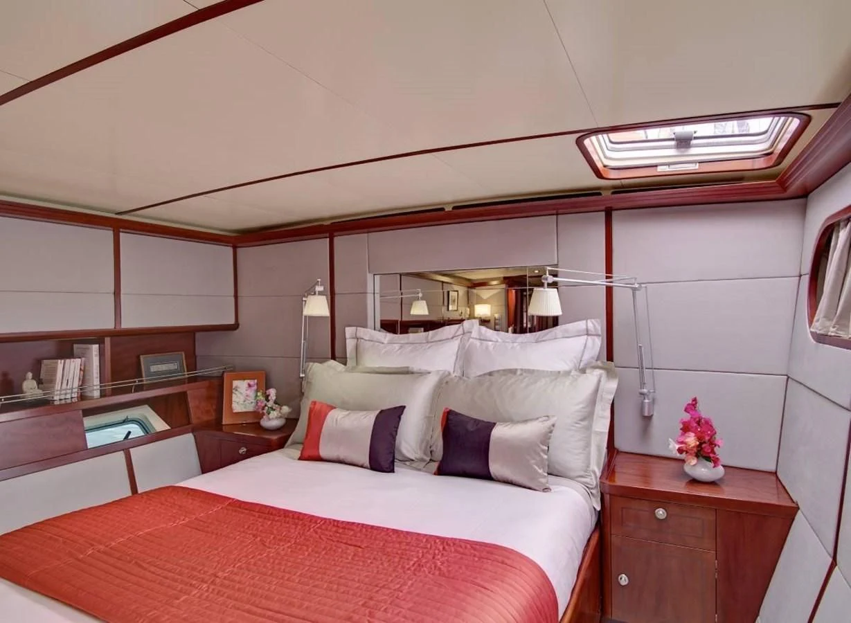 a bed with a red and white bed spread and a white bed spread aboard MIROVIA Yacht for Charter